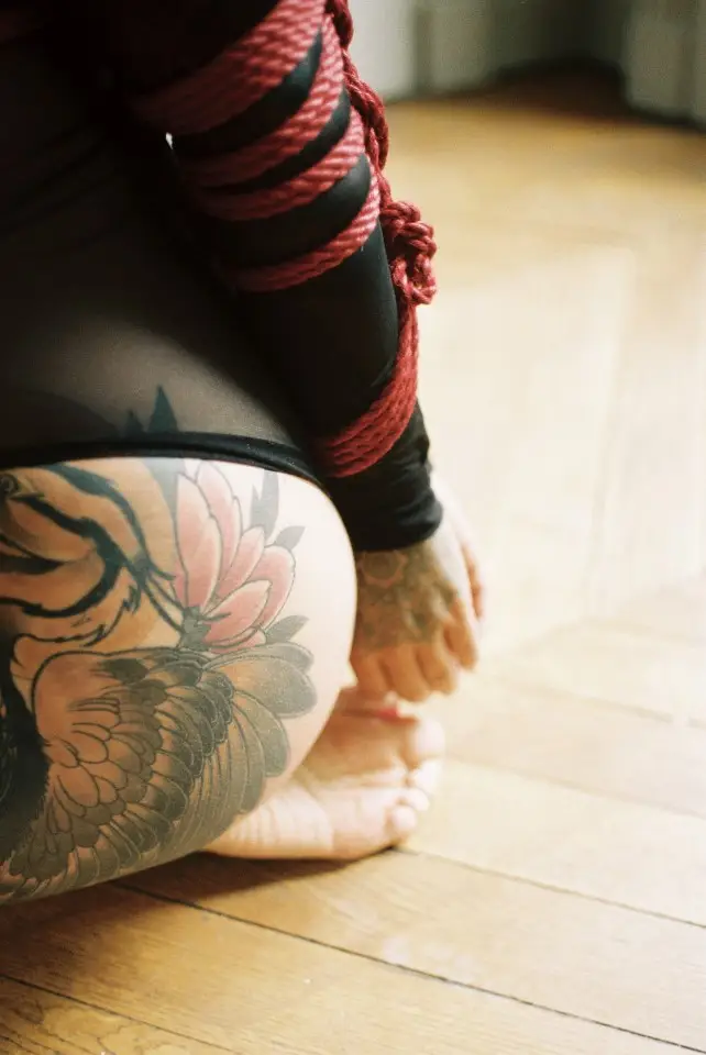 shibari avec cordes rouges sur modèle tatouée